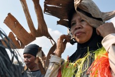 Two women get ready to perform Gejog Lesung by placing dried banana leaves on their heads. JP/Magnus Hendratmo