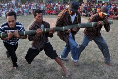Four men play Bambu Gila (crazy bamboo), a mystical ritual usually performed on Indonesia’s Maluku Islands, where a group of strong men struggle to control a piece of bamboo, which moves uncontrollably as if it were possessed by a supernatural power. JP/Magnus Hendratmo