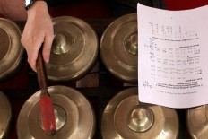 A gamelan instrument is played while a note is laid on top of it during rehearsal. JP/Maksum Nur Fauzan