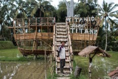 Ride the ship: Nyoman Wastu creates his own tourist attraction from bamboo. His paddy field is located far from the main street, so he has to make an effort to attract tourists. JP/ Anggara Mahendra