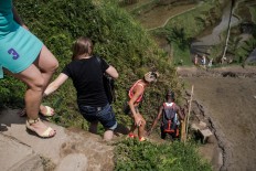 Step by step: Foreign tourists climb down the paddy terrace wall in Ceking. JP/ Anggara Mahendra