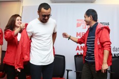Indonesian Solidarity Party (PSI) chairwoman Grace Natalie (left) and secretary-general Raja Juli Antoni help musician Giring Ganesha put on a PSI jacket at the party's headquarters in Jakarta on Sept. 6, 2017.