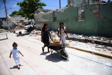 People walk by buildings knocked down by 
a quake, in Ixtaltepec, Oaxaca, Mexico, on September 9, 2017. Mexico's most powerful earthquake in a century killed at least 35 people, officials said, after it struck the Pacific coast, wrecking homes and sending families fleeing into the streets. AFP/ Ronaldo Schemidt