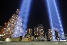 People gather on a rooftop as the 'Tribute in Light' illuminates the night sky, on September 10, 2017 in New York City, on the eve of the anniversary of the September 11, 2001 terror attacks. Commemorations are being held on the 16th anniversary of the 9/11 terror attacks, with President Donald Trump expected to speak at a ceremony for the 184 people killed at the Pentagon in Washington, DC. AFP/ Kena Betancur