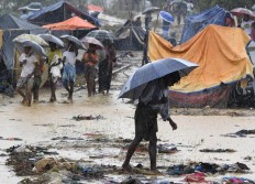 A Rohingya refugee holds an umbrella during rain in Bangladesh's Balukhali refugee camp on September 17, 2017. Monsoon rain amid a drive to move hundreds of thousands of Muslim Rohingya out of makeshift camps added to the misery of the refugees on September 17 who have fled violence in Myanmar for Bangladesh. AFP/ Dominique Faget 