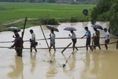 Rohingya Muslim refugees cross floodwater in Thyangkhali refugee camp near the Bangladesh town of Ukhia on September 17, 2017. Heavy monsoon rain heaped new misery September 17 on hundreds of thousands of Muslim Rohinyga stuck in makeshift camps in Bangladesh after fleeing violence in Myanmar, as authorities started a drive to force them to a new site. The United Nations says 409,000 Rohingyas have now overwhelmed Cox's Bazar since August 25 when the military in Buddhist-majority Myanmar launched operations in Rakhine state. AFP/ Dominique Faget 
