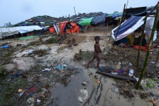 A Rohingya Muslim refugee child walks through Balukhali refugee camp near the Bangladesh town of Gumdhum on September 17, 2017. Heavy monsoon rain heaped new misery September 17 on hundreds of thousands of Muslim Rohinyga stuck in makeshift camps in Bangladesh after fleeing violence in Myanmar, as authorities started a drive to force them to a new site. The United Nations says 409,000 Rohingyas have now overwhelmed Cox's Bazar since August 25 when the military in Buddhist-majority Myanmar launched operations in Rakhine state. AFP/ Dominique Faget 