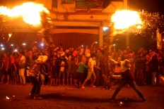 Watch out: Spectators react as two combatants wield flaming torches. JP/ Maksum Nur Fauzan