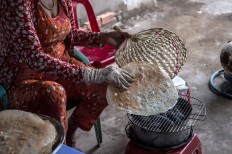In this picture taken on July 7, 2017, Nguyen Thi Hue cooks rice paper over a makeshift charcoal stove at the exit of a ferry crossing near Thuan Hung Village in the Mekong Delta. Stuffed, rolled, baked or fried: rice paper rules in food-obsessed Vietnam, where hungry diners have spurned factory-made versions for homespun ones, propping up a thriving cottage industry in the Mekong Delta.