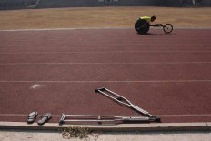 Crutches lie discarded alongside a track as a track-and- field athlete trains for the wheelchair race. JP/Maksum Nur Fauzan