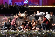 People scramble for shelter at the Route 91 Harvest country music festival after apparent gun fire was heard on October 1, 2017 in Las Vegas, Nevada. A gunman has opened fire on a music festival in Las Vegas, leaving at least 20 people dead and more than 100 injured. Police have confirmed that one suspect has been shot. The investigation is ongoing. AFP/Getty Images/David Becker