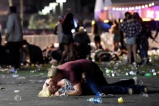 A man lays on top of a woman as others flee the Route 91 Harvest country music festival grounds after a active shooter was reported on October 1, 2017 in Las Vegas, Nevada. A gunman has opened fire on a music festival in Las Vegas, leaving at least 2 people dead. Police have confirmed that one suspect has been shot. The investigation is ongoing. AFP/Getty Images/David Becker