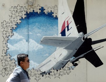 A Malaysian man walks in front of a mural of missing Malaysia Airlines MH370 plane in a back-alley in Shah Alam on March 8, 2016. Malaysia and Australia said they remained 