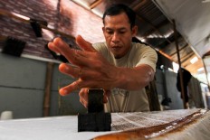 Consistency: A batik artisan carefully uses a copper stamp to print a batik motif. JP/Ibrahim Irsyad