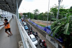 Motorists drive past a road closure banner in Manggarai, South Jakarta, on Oct. 26, 2016. Violent quarrels and brawls among residents around the Manggarai area are common with no one entirely clear as to the cause of the feud.