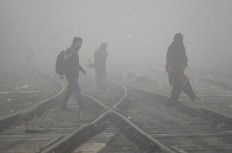 Indian commuters cross railway lines in dense fog and air pollution in Jalandhar on Nov. 7, 2017.