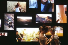 People walk past LED television monitors at the Toshiba stand at a trade fair in Berlin, Germany. 