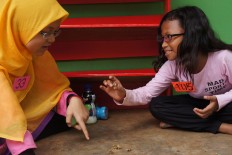 Two girls play 'bola bekel' during an event in the Traditional Games Return campaign on Sunday. 