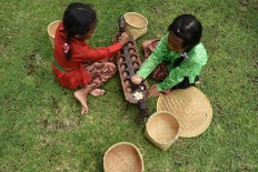 Ready, set, count: Two girls play dakon, a traditional game, during the Ajar Pusaka Budaya event. JP/ Aman Rochman