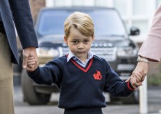 This file photo taken on September 07, 2017 shows Britain's Prince George (center) accompanied by Britain's Prince William (left), Duke of Cambridge arriving for his first day of school at Thomas's school where he is met by Helen Haslem (right) head of the lower school in southwest London.