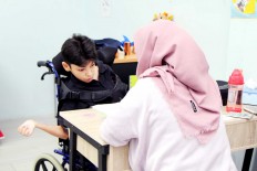 Working hard: A boy with special needs focuses on his work while being assisted by his teacher.