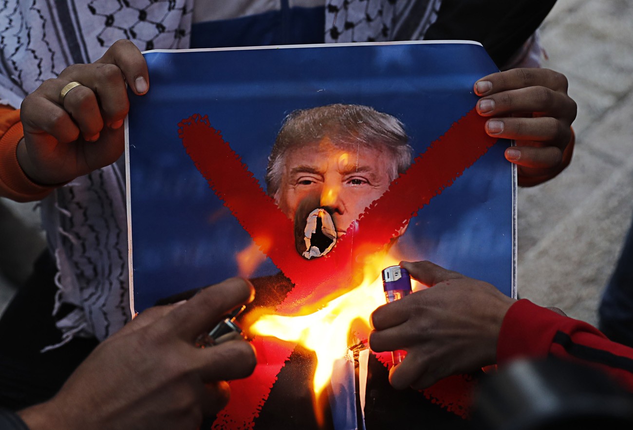 Palestinian youths set a portrait of US President Donald Trump on fire after his recognition of Jerusalem as Israel's capital, during a demonstration outside Damascus Gate in Jerusalem's Old City on Dec.11
