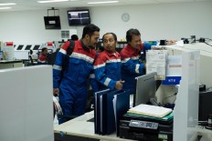 Coordination: Three workers engage in a discussion in the control room prior to handing over their work shifts. JP/ Jerry Adiguna
