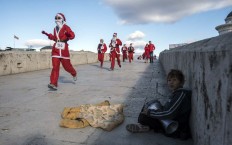 A child plays the tambourine while men dressed as Santa Claus take part in the traditional New Year's Santa Claus race in Skopje, on December 24, 2017. AFP/Robert Atanasovski