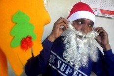 He puts on his fake Santa beard. JP/Maksum Nur Fauzan