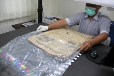 Handled with care: An employee stores an old newspaper into a plastic cover. JP/Maksum Nur Fauzan.