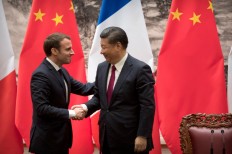 French President Emmanuel Macron (left) and Chinese President Xi Jinping shake hands after a joint press briefing at the Great Hall of the People in Beijing on Jan. 9, 2018. 