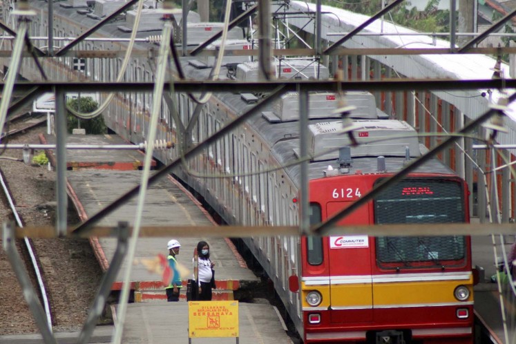 A Commuter Line train passes waiting passengers on Jan. 12, 2018, as it pulls into Cilebut Station in Bogor, West Java.