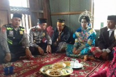 A bride and groom sit among police officials after their customary wedding in Gowa regency, South Sulawesi, on Jan. 15, 2018. The couple were married under the watch of police personnel after they were caught alone in a fruit orchard in their village.