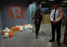 An employee (left) of online portal Rappler heads out from their editorial office in Manila on Jan. 15, 2018, while a private security guard stands. 