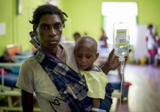 A Papuan woman carrying a drip looks on with her child at a local hospital handling measles and malnutrition patients in Agats, the capital of Asmat district in Indonesia's easternmost Papua province, on January 25, 2018. Some 800 children have been sickened by a measles-and-malnutrition outbreak in Indonesia's remote Papua province, officials said January 25, with as many as 100 people, mostly toddlers, feared to have been killed in the outbreak. AFP/ Bay Ismoyo