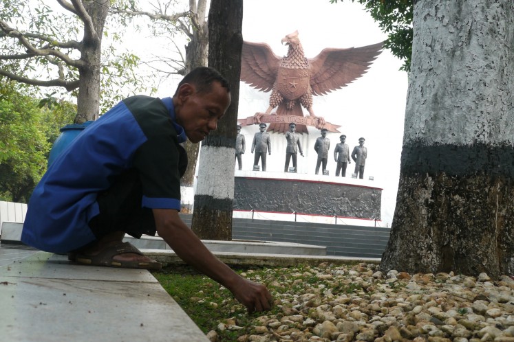 A man cleans up lawn at the the Pancasila Sakti (Sacred Pancasila) monument complex in Lubang Buaya, East Jakarta, in this Sept. 28, 2013 photo.