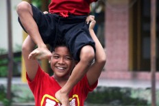Teamwork: A barongsai dancer smiles as he lifts his partner. JP/ Maksum Nur Fauzan