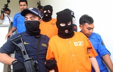 Busted: The Bali Police's anti narcotics squad personnel escort Siegfried Karl Achim Ruckel, 55, for a press conference on Feb.22. Ruckel was arrested over an alleged attempt to smuggle drugs into Bali. 