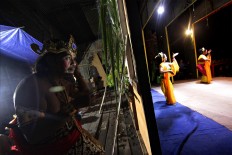 An actor gets ready while two dancers perform on stage. JP/Aditya Sagita