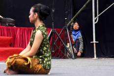 An elderly lady crouches on the asphalt to watch the performance. JP/Maksum Nur Fauzan