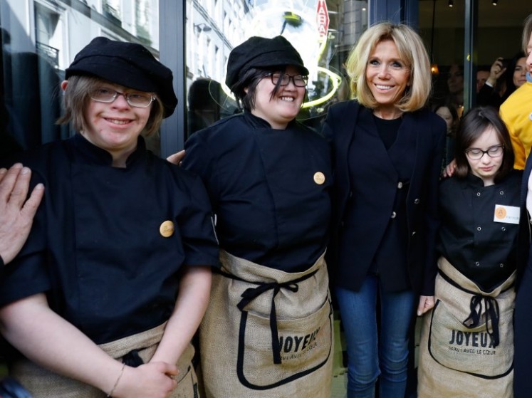 The wife of French President Brigitte Macron poses with handicapped and autistics employees of the Cafe Joyeux restaurant in Paris on March 21, 2018. 