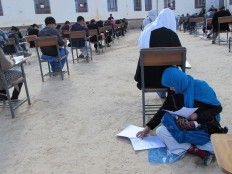 This photo obtained from the Facebook account of Afghan professor Yahya Erfan and taken on March 16, 2018 shows Afghan student Jahantab Ahmadi (bottom R), 25, sitting on the ground as her baby lays on her lap as she takes an entrance exam for Nasir Khusraw private university, in the central city of Nili, the provincial capital of Daykundi province. 