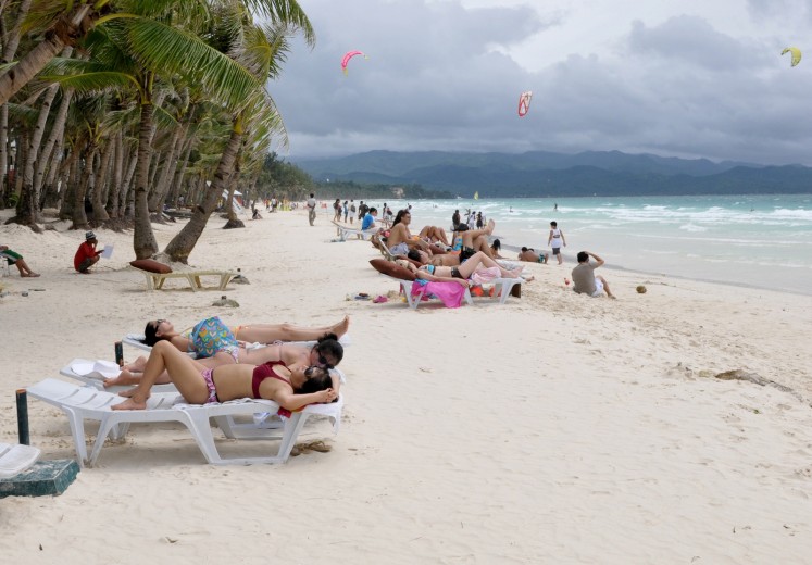 Tourists sunbathe on the fabled beach of Boracay Island on November 9, 2008.