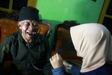 An elderly man smiles while receiving treatment. JP/Maksum Nur Fauzan