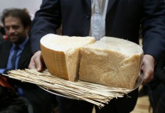 A man presents pieces of Parmigiano Reggiano (parmesan) during a sale of fine food to raise funds for the French Red Cross on December 18, 2012 French auction house Artcurial in Paris. 