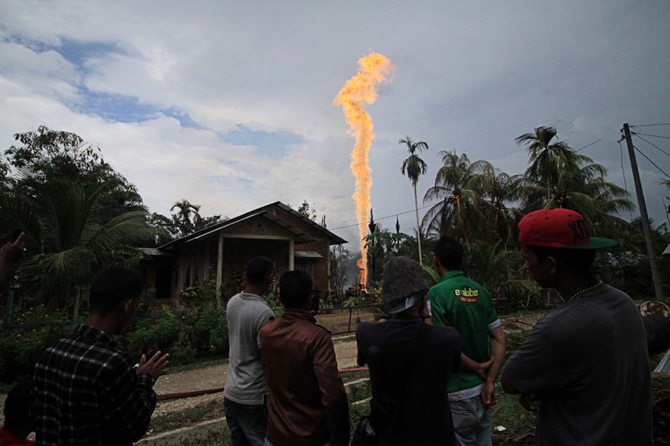 People watch on April 25, 2018, as a column of flame shoots out from an illegal oil well in Pasi Puteh village, East Aceh, Aceh, sparking a blaze in which at least 11 people were killed and more than 40 injured.