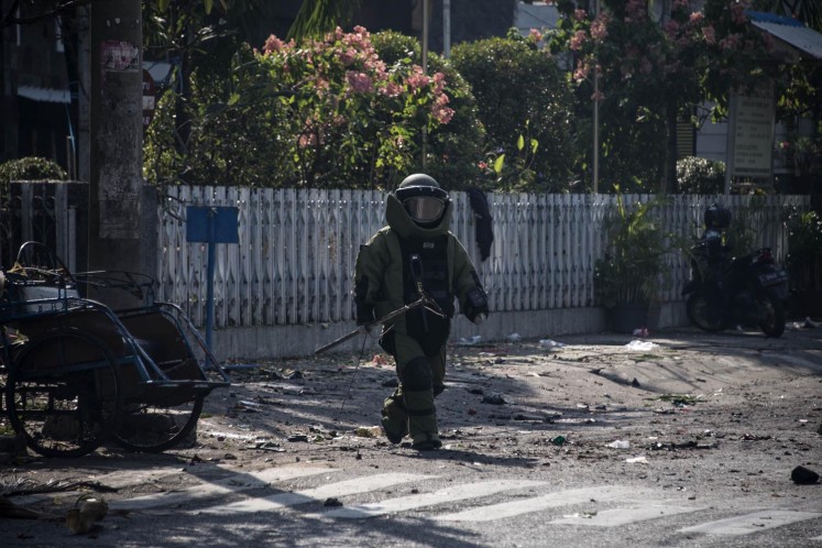 An Indonesian bomb squad member examines the site following an alleged suicide bomb attack outside a church in Surabaya on May 13.
