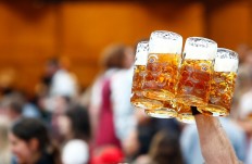 A waiter carries glasses of beer during the opening day of the 184th Oktoberfest in Munich, Germany, September 16, 2017.
