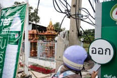 A spirit house is located underneath a billboard in Ayutthaya, Thailand. JP/Anggara Mahendra