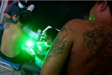 Shine a light: An employee of the service uses a tool that shines green while removing tattoos from clients. JP/Maksum Nur Fauzan